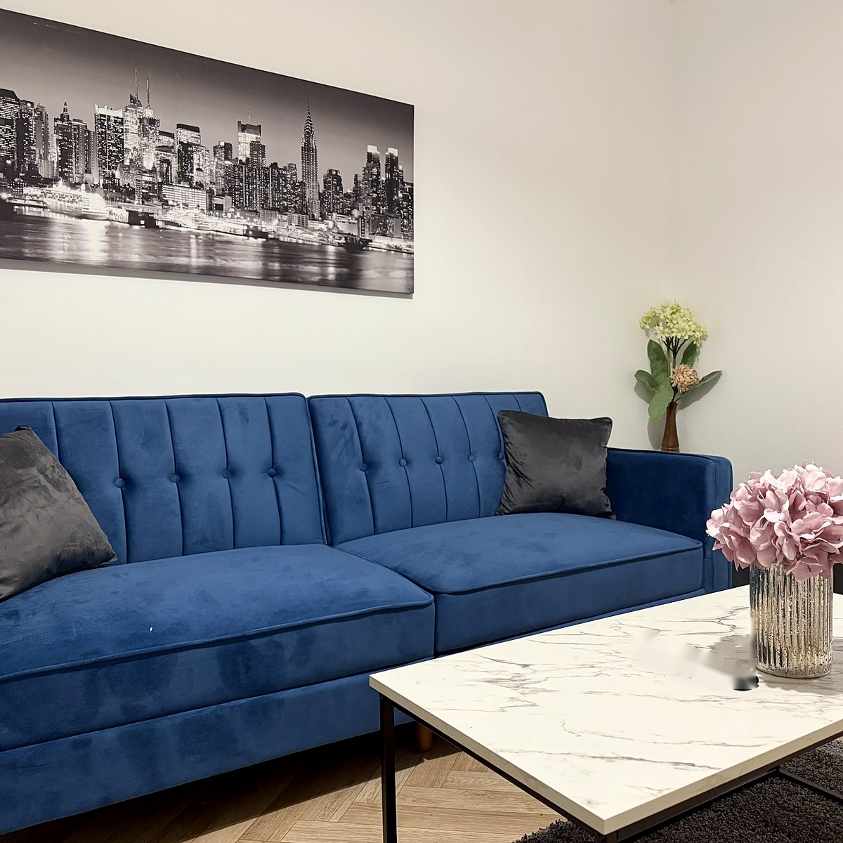 Living room with a blue velvet sofa and marble coffee table