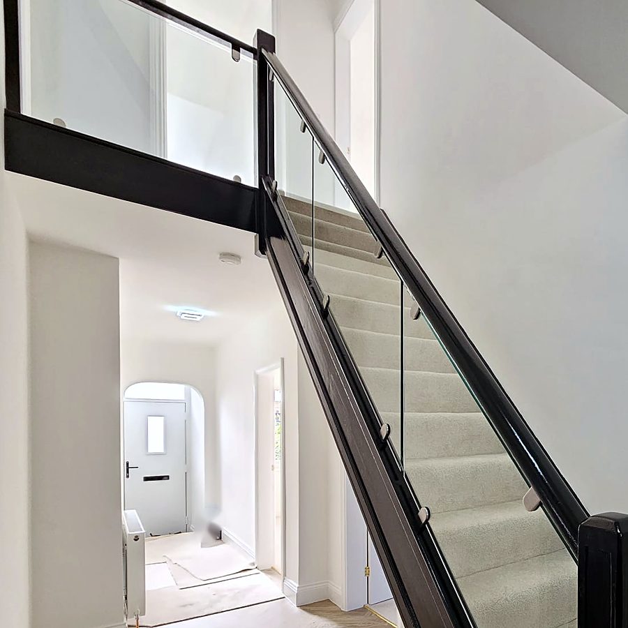 Hallway with a black and glass staircase and herringbone floor