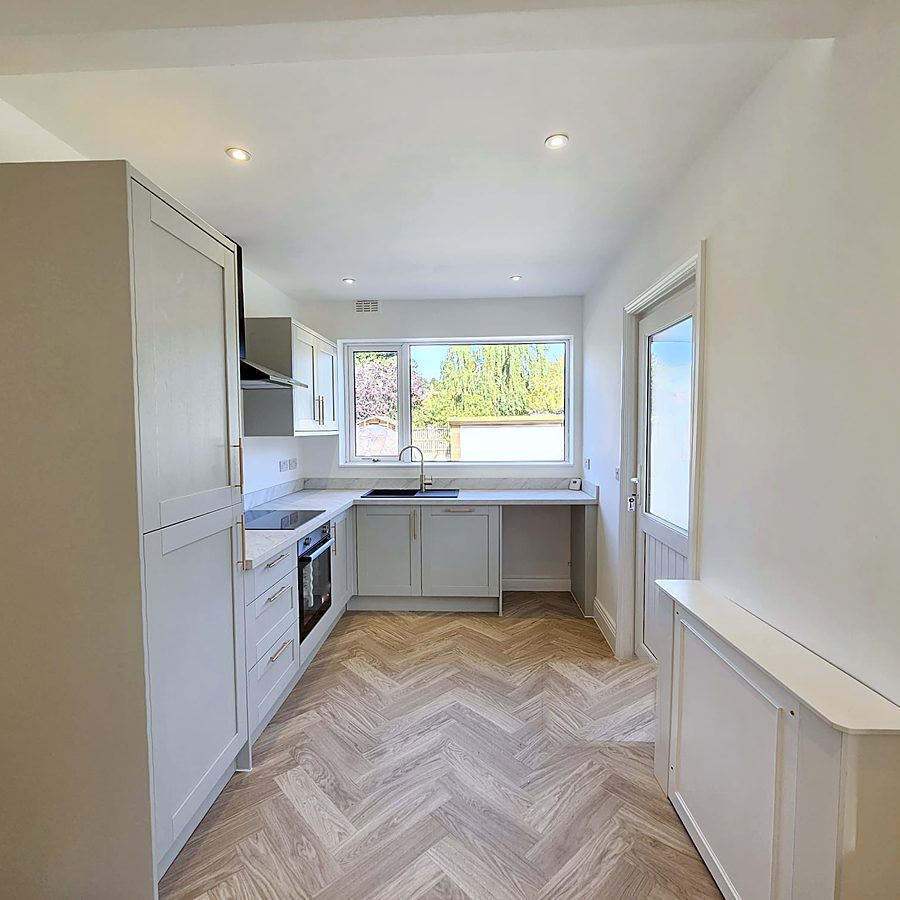 Sage shaker kitchen with herringbone floor and a garden view