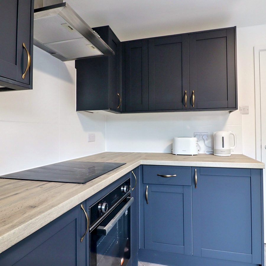 Navy shaker kitchen with oak-effect worktop and brass handles