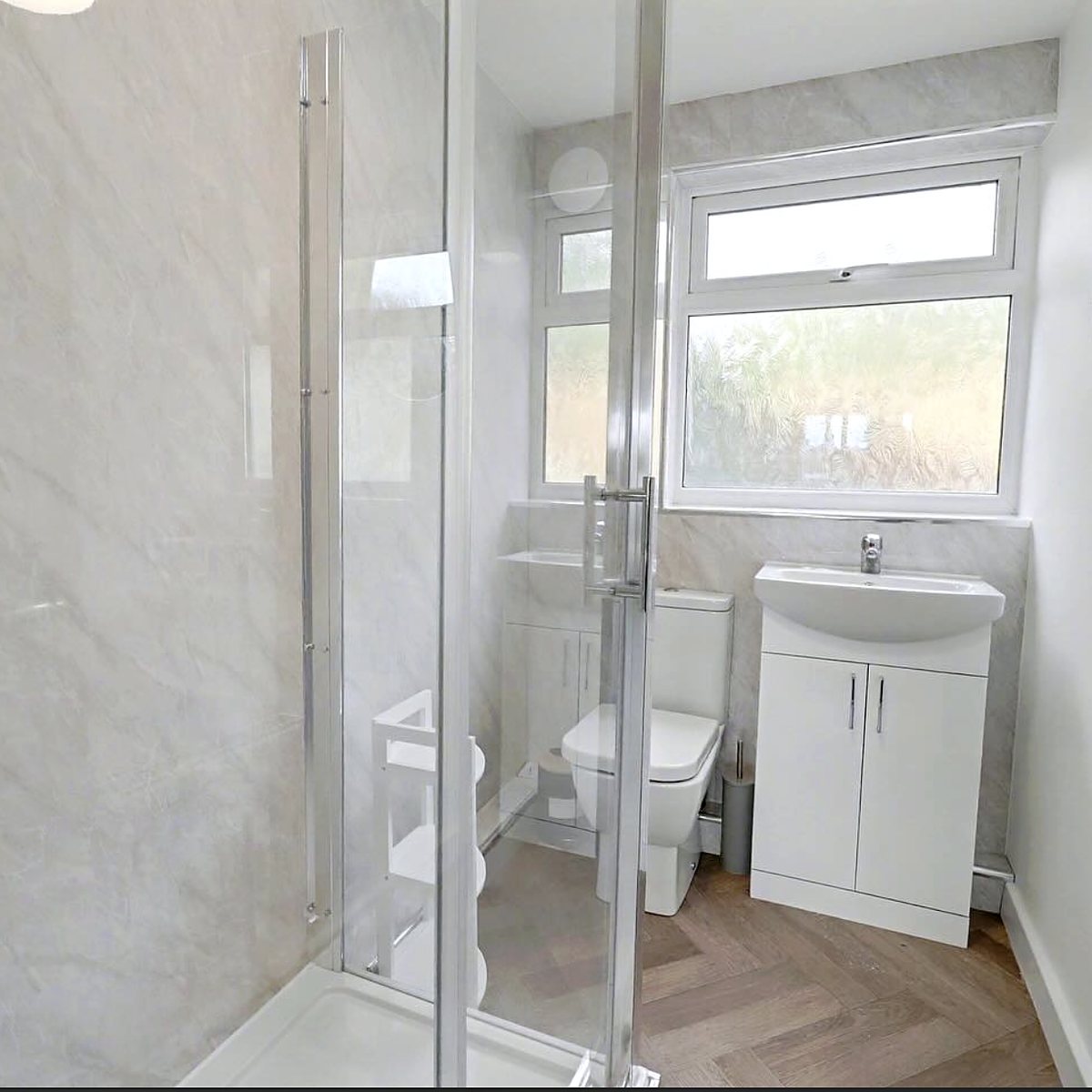 Shower room with marble-effect panels and herringbone floor